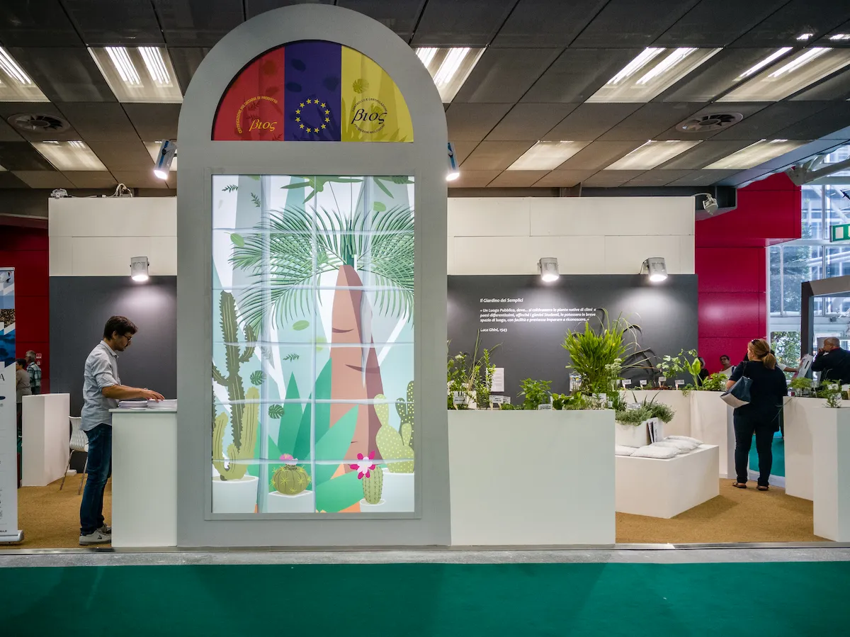 Portale d'ingresso a forma di arco con grafica botanica retroilluminata e loghi di certificazione biologica.